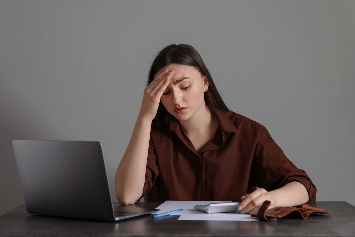 Mulher preocupada usando calculadora para somar as taxas ocultas e gas fees de transações com criptomoedas na JumpTask.