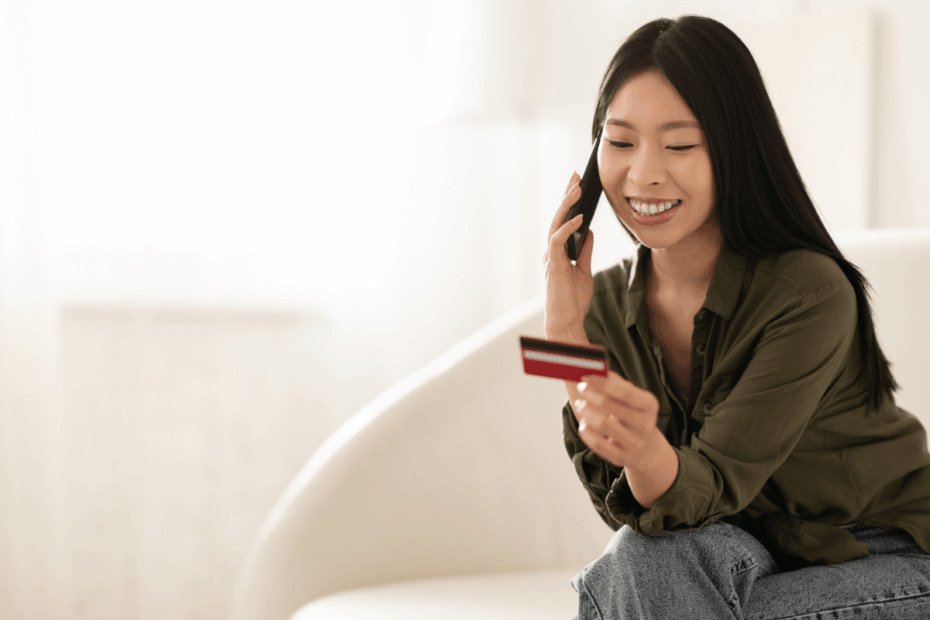 Mulher sorrindo ao telefone segurando um cartão de crédito, ilustrando a satisfação e a segurança dos clientes ao usar a Méliuz.