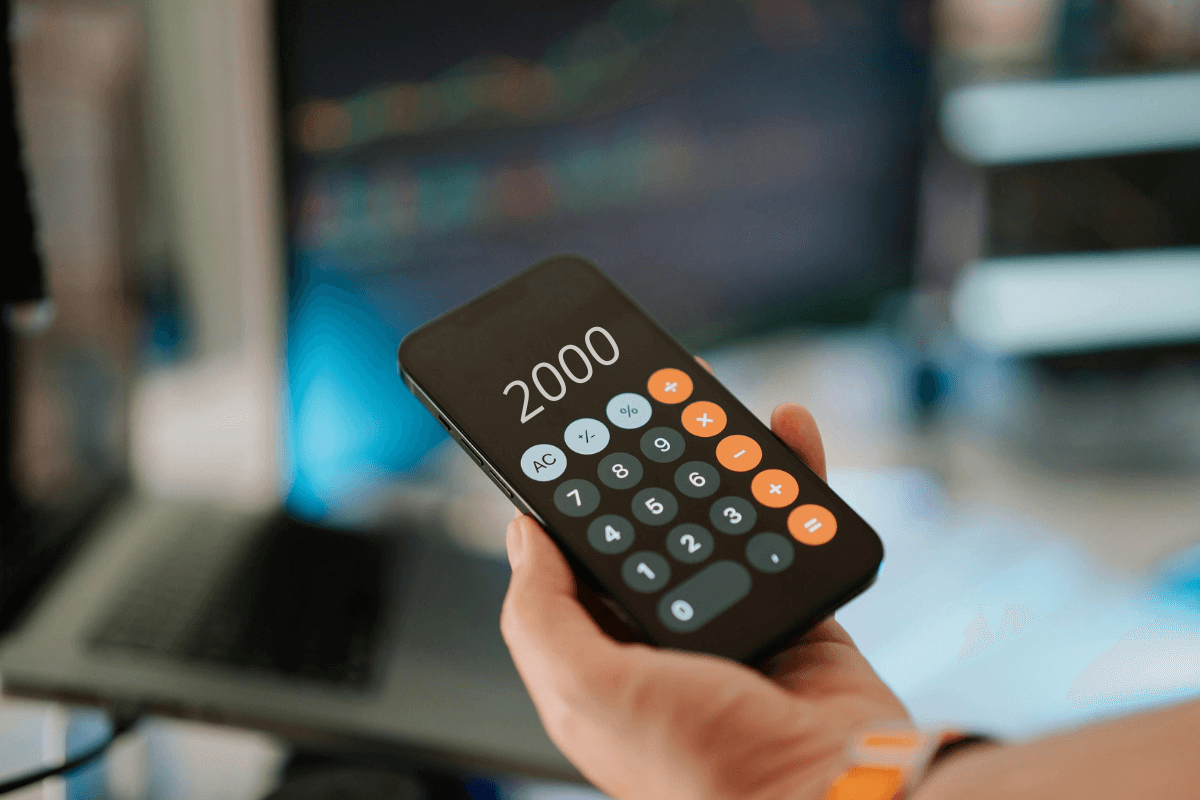 Mão segurando um celular exibindo o número 2000 na calculadora, ilustrando a análise matemática do valor real dos pontos no Microsoft Rewards.