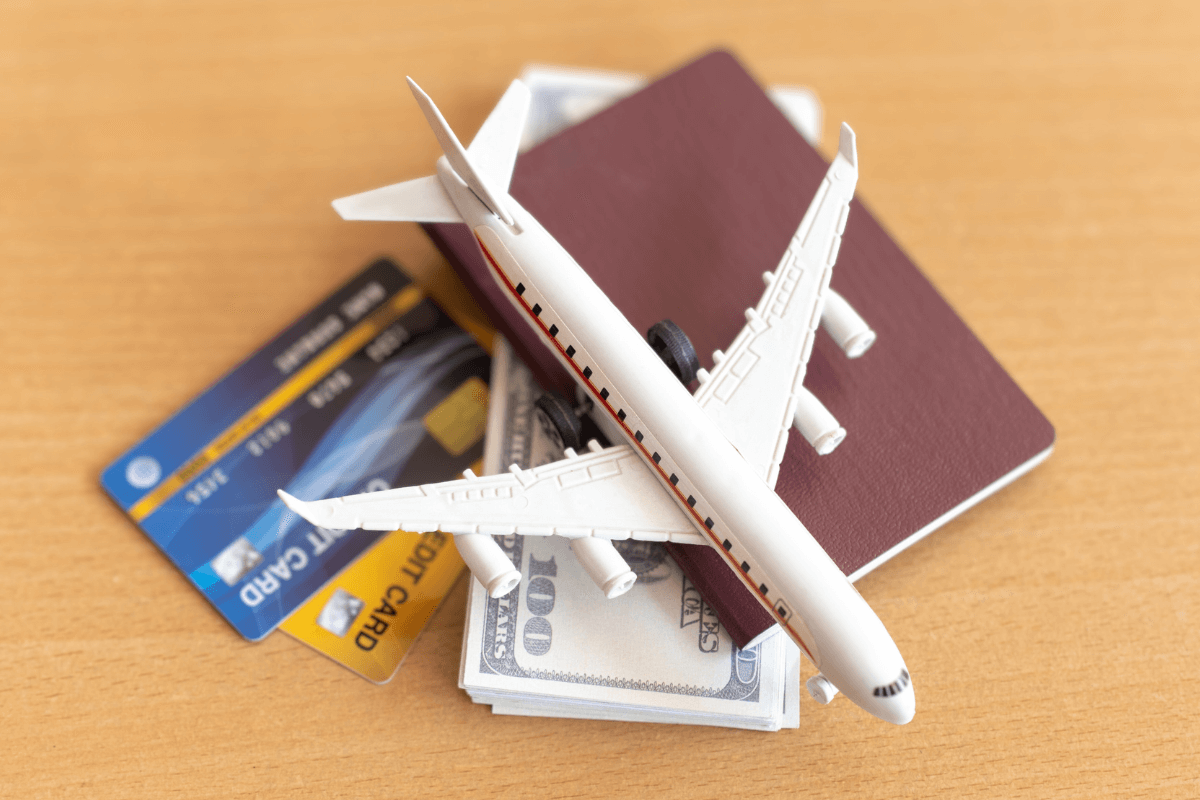 Miniatura de avião sobre passaporte, cartão de crédito e notas de dólar, ilustrando o alto custo e complexidade dos programas de milhas tradicionais em comparação ao Microsoft Rewards.