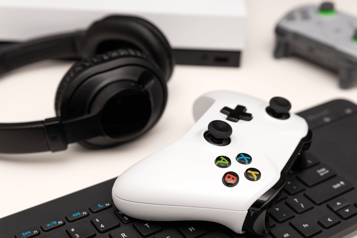 Fone de ouvido preto e um controle branco de xbox em cima de um teclado na mesa, simbolizando a venda de hardware da Microsoft Store.