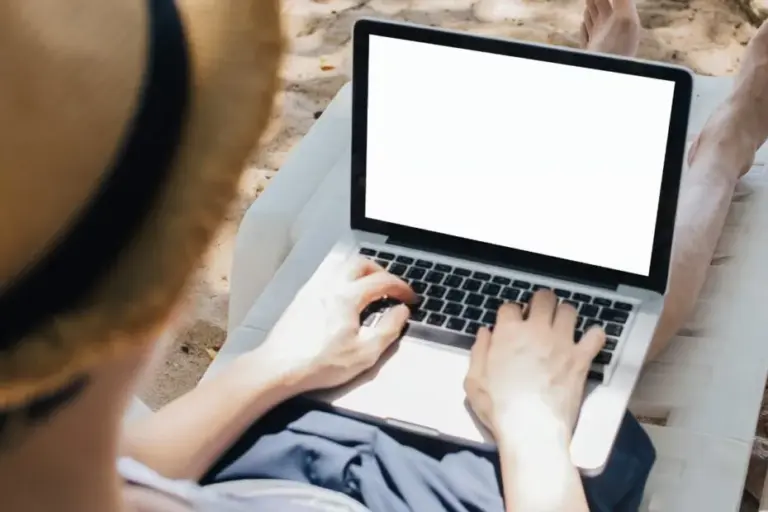 Pessoa trabalhando remotamente na praia com notebook, ilustrando o objetivo de como tirar o visto de Nômade Digital na Espanha