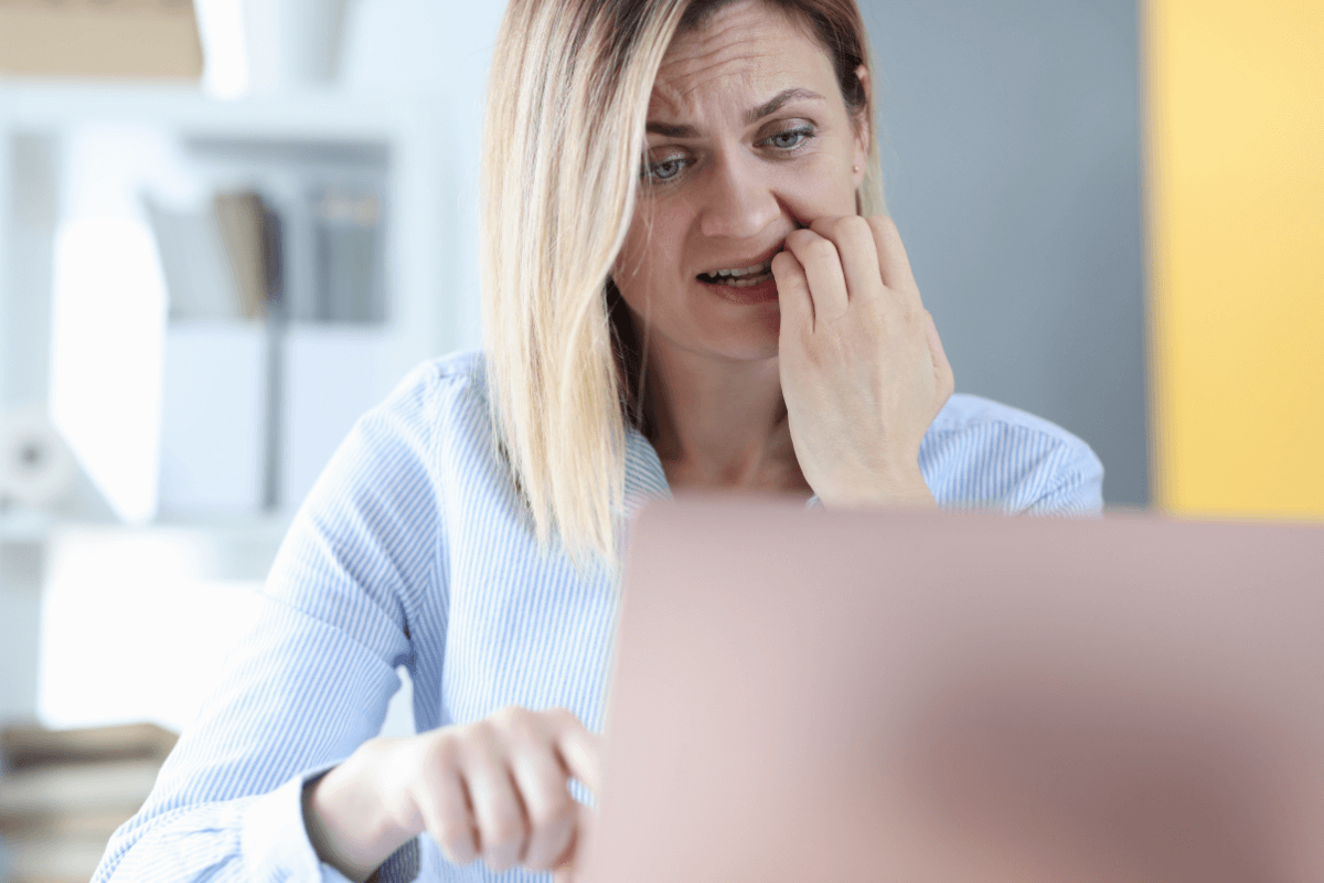 Mulher preocupada olhando para o notebook, representando as dúvidas e desafios sobre se é lucrativo trabalhar como afiliado no mercado digital atual.