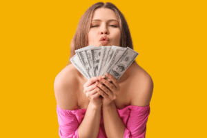 Mulher feliz segurando um leque de notas de dólar sobre fundo amarelo, simbolizando os lucros e a renda extra obtida nos melhores sites para ganhar dinheiro respondendo pesquisas online.