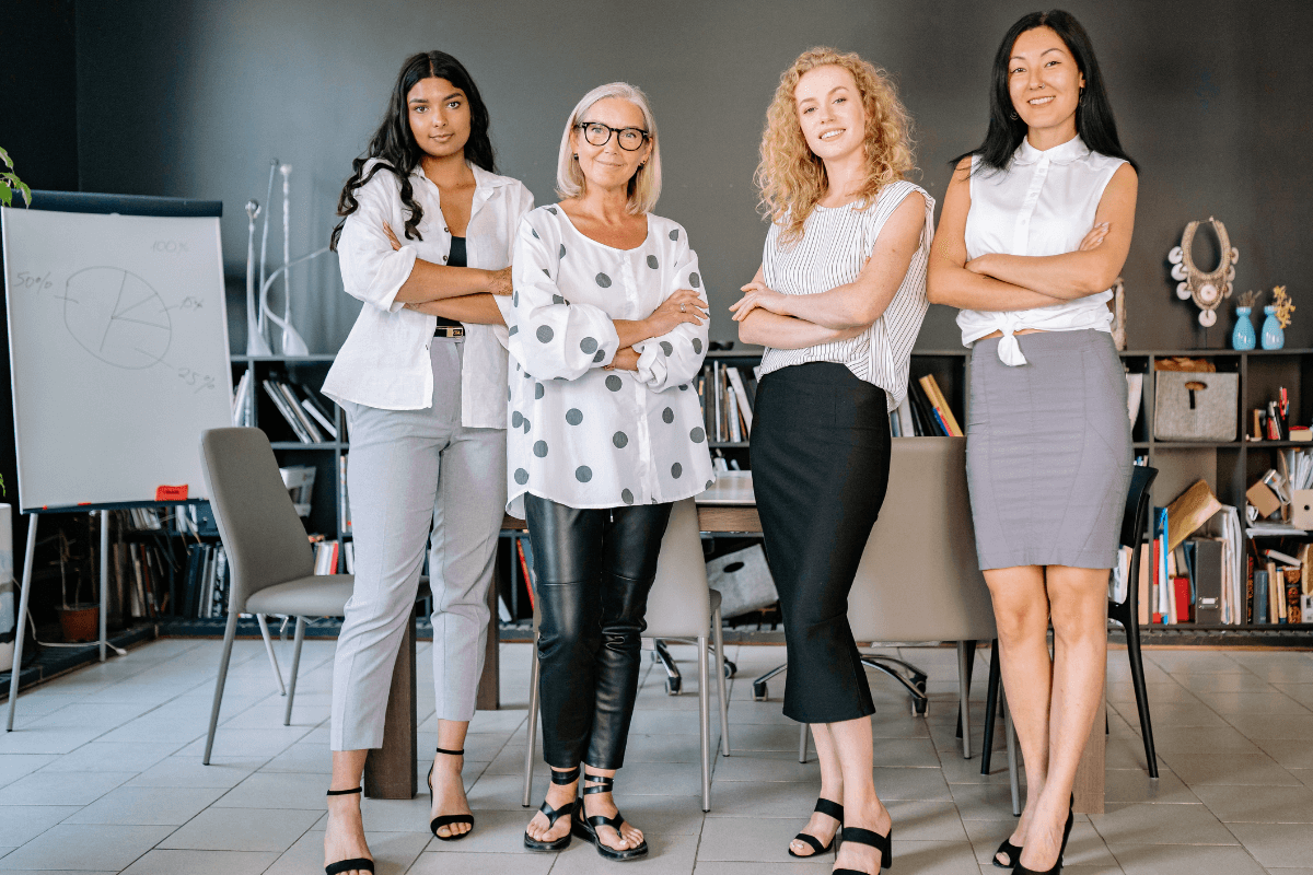 Grupo de mulheres de negócios com postura confiante em um escritório, ilustrando a profissionalização e a mentalidade empreendedora necessária no marketing digital.