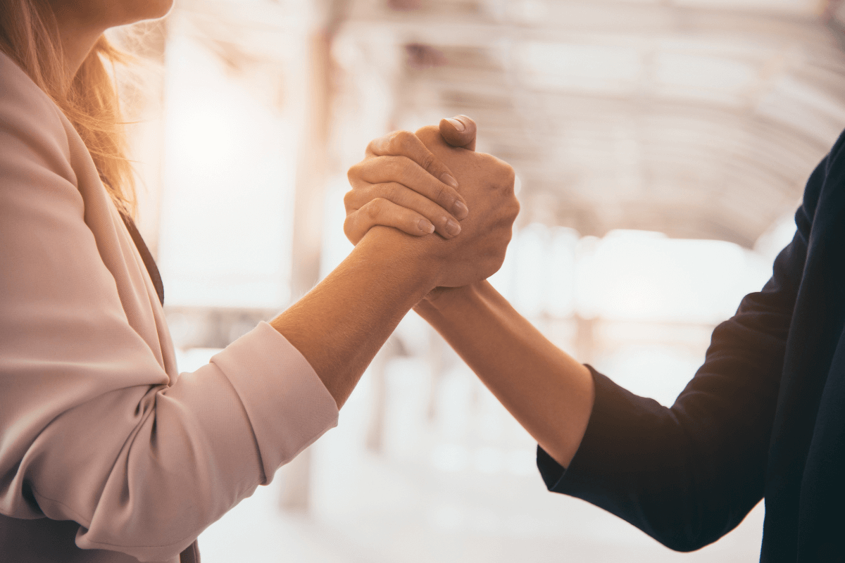 Aperto de mãos firme entre duas pessoas em ambiente profissional, simbolizando o acordo de parceria honesta e de longo prazo entre o afiliado e o Mercado Livre.