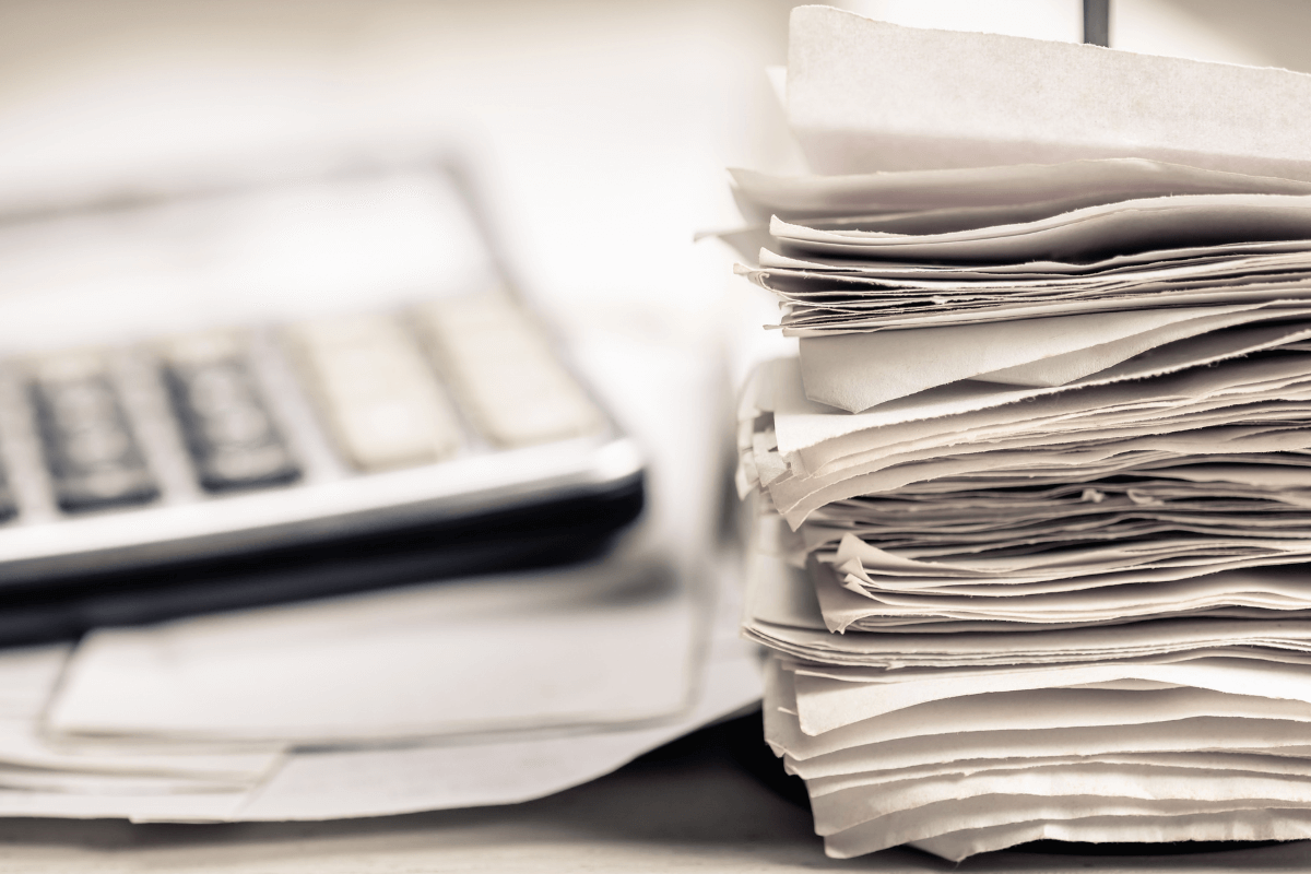 Pilha de notas fiscais e cupons ao lado de uma calculadora, ilustrando a importância da organização física para ganhar dinheiro com cashback.