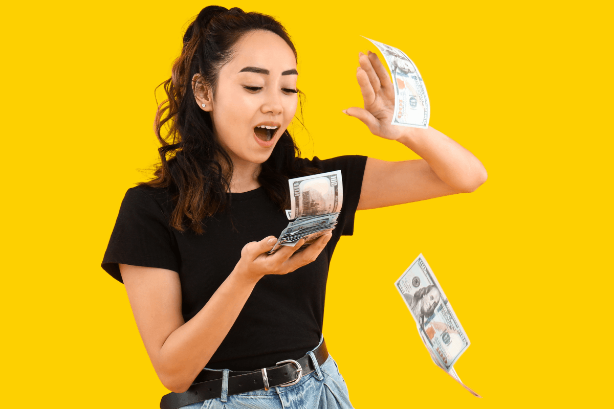 Mulher jovem com expressão de surpresa e felicidade segurando e jogando notas de dinheiro em um fundo amarelo vibrante, ilustrando o potencial de faturamento e renda extra como afiliado do Mercado Livre.